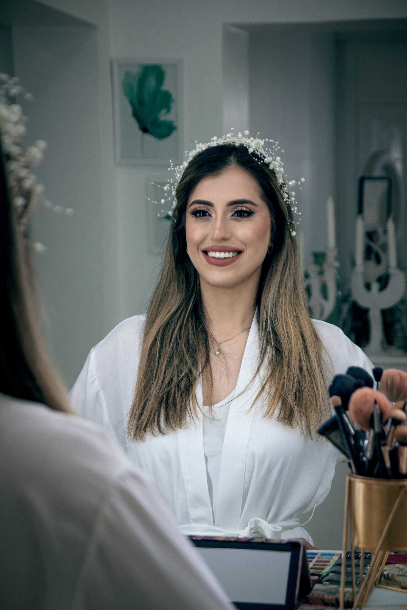 a woman in a white shirt is smiling and holding makeup brushes